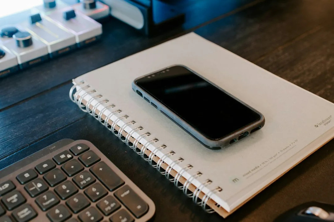 Teléfono sobre un cuaderno junto al teclado, listo para silenciar notificaciones